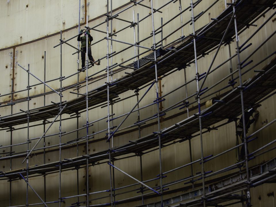 Worker male assembly in progress storage tank oil inspection scaffolding work at high